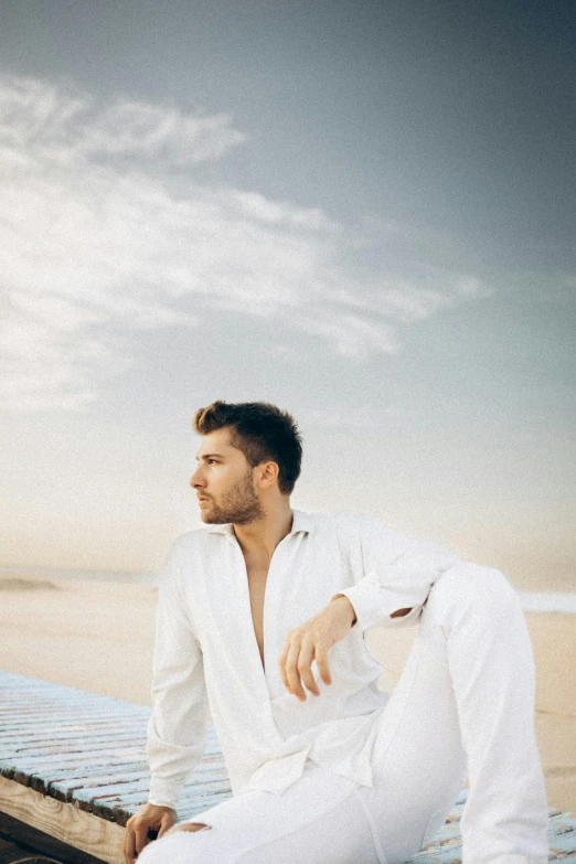 a man with a beard sits on a pier