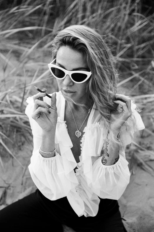 a woman with sunglasses smokes in the desert