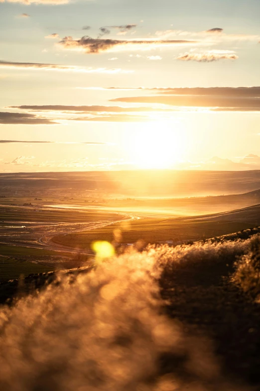 the sun setting over mountains with rolling steam coming out