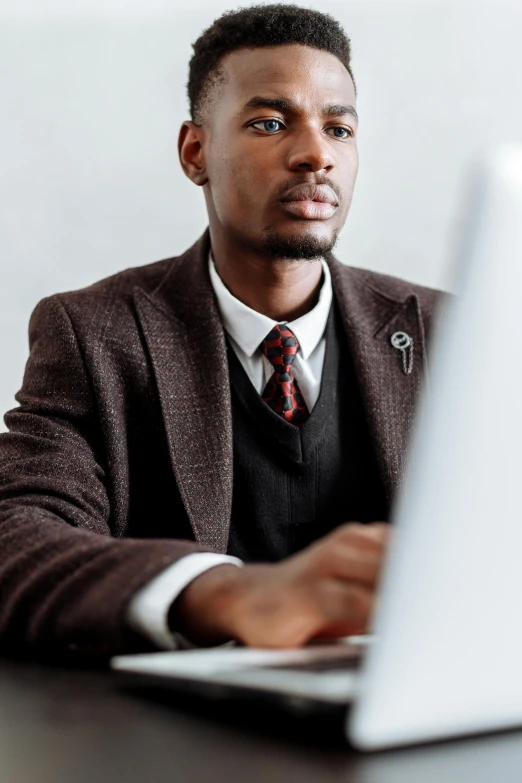 man in suit sitting in front of laptop computer