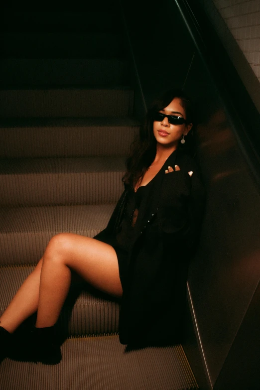 a woman wearing sunglasses and dress is posing on stairs