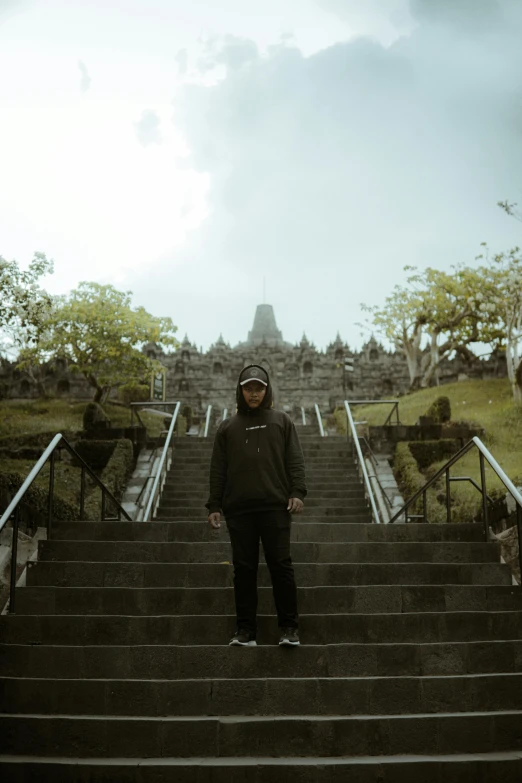 a man standing on a set of stairs with trees on each side