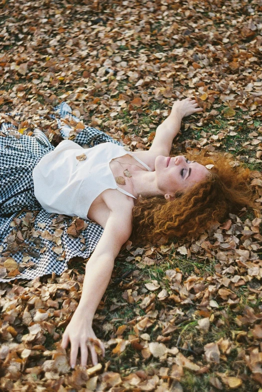 a girl lays on the ground amongst leaves