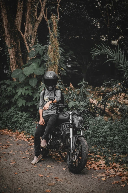 a man on a motorcycle in front of some trees