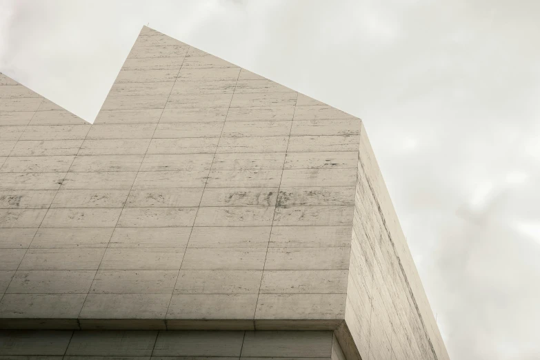 a side view of a triangular building, against a cloudy sky