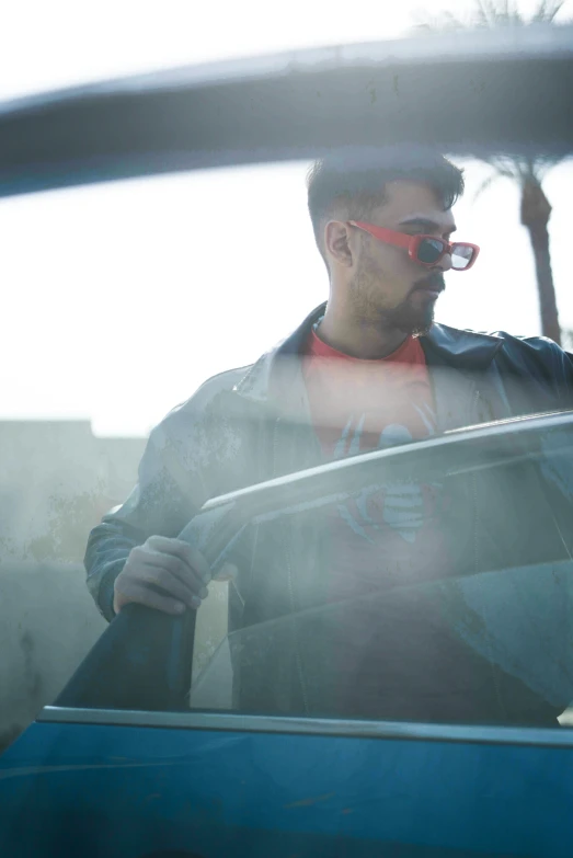 man with glasses sitting behind a car driving