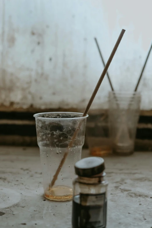 there is a glass cup with a straw next to a bottle