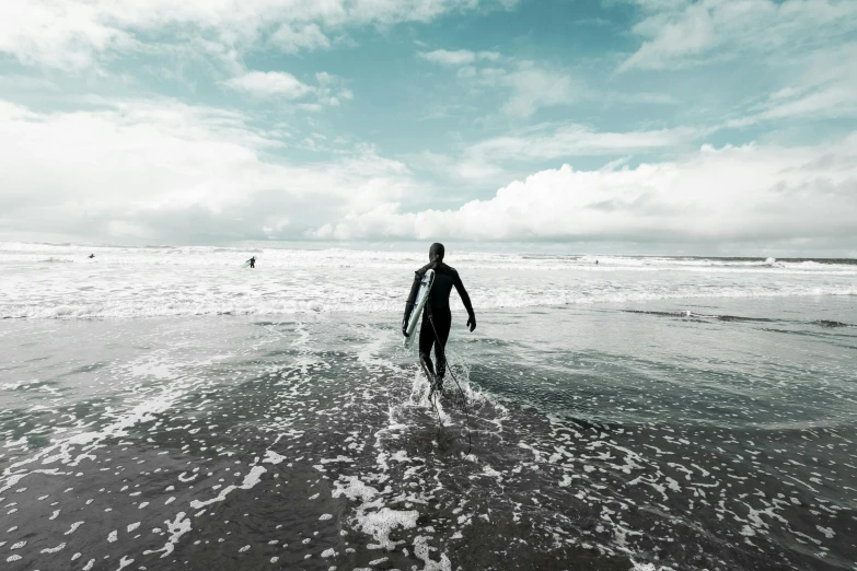 a surfer carrying his board out into the ocean