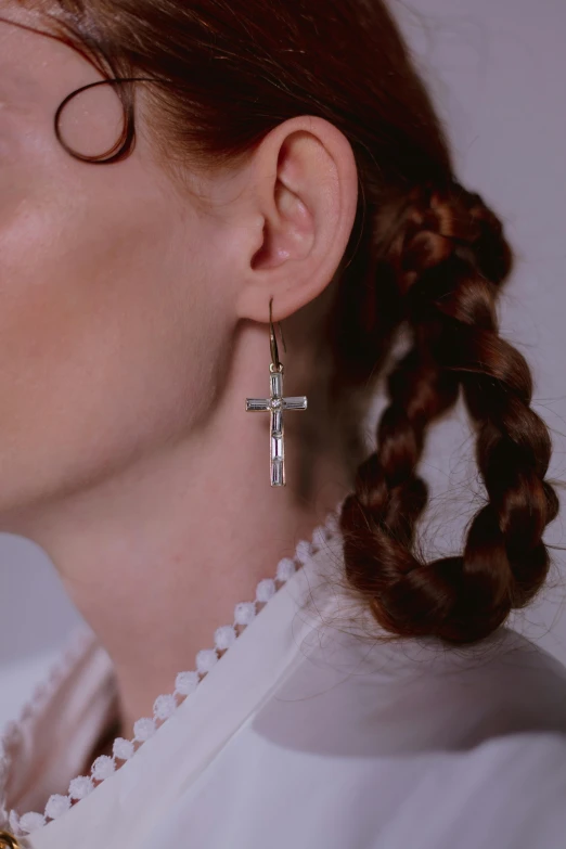 a close up of a woman wearing large cross earrings