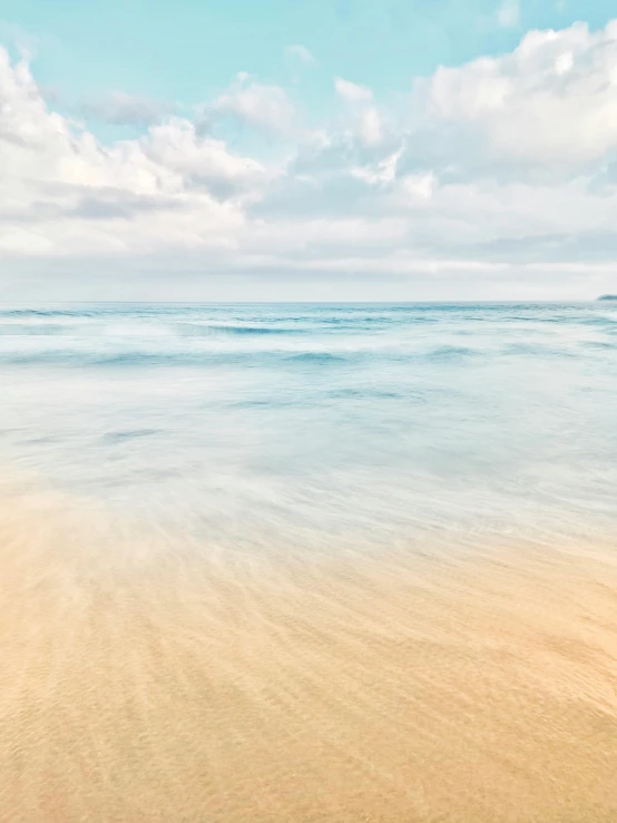 a sandy beach near an ocean and clouds