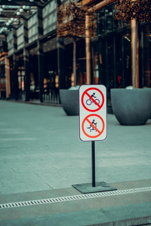 a white and red no bicycles sign on sidewalk