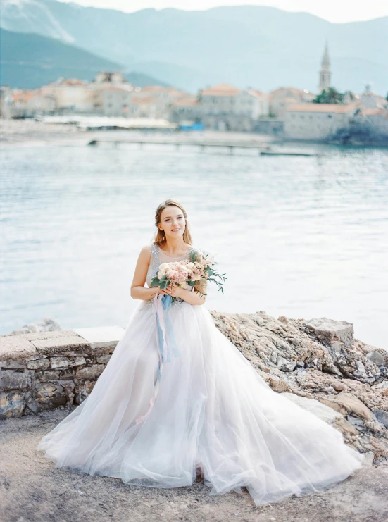 a woman standing by the water holding flowers