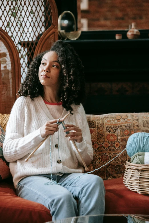 a woman sitting on a couch with a crochet knitting hook