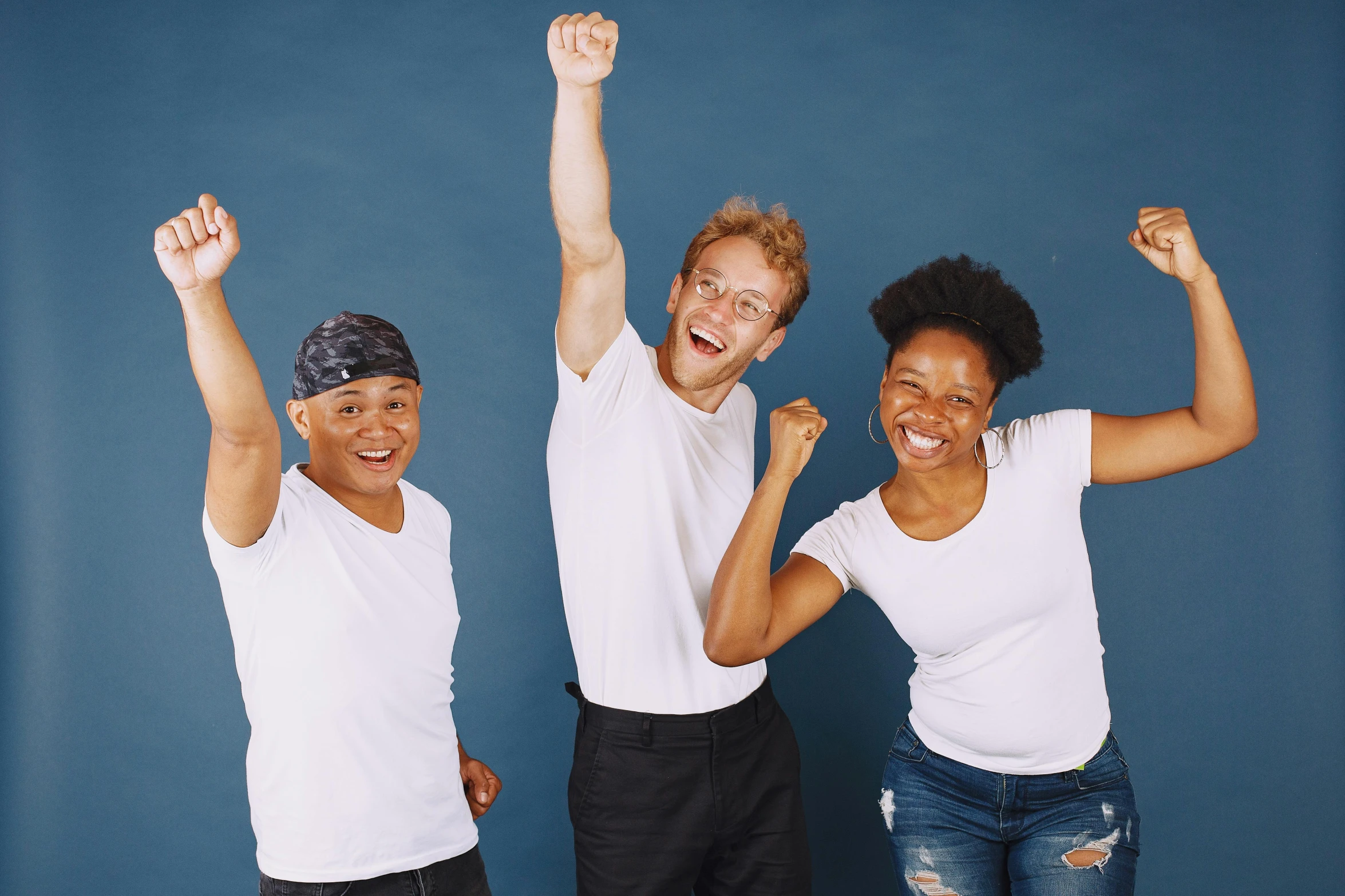 three young people standing and raising their fists in the air