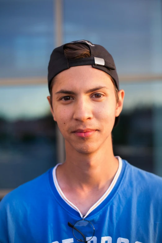 a young man with glasses, in front of a building