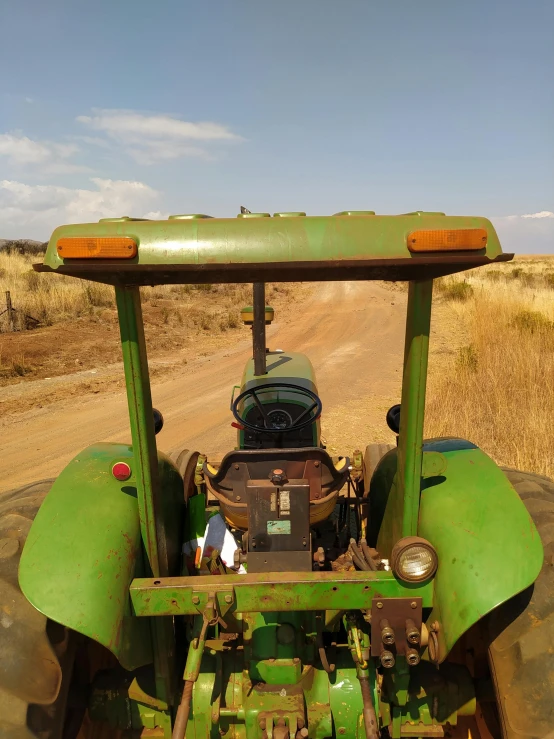 the front end of a green tractor in the dirt