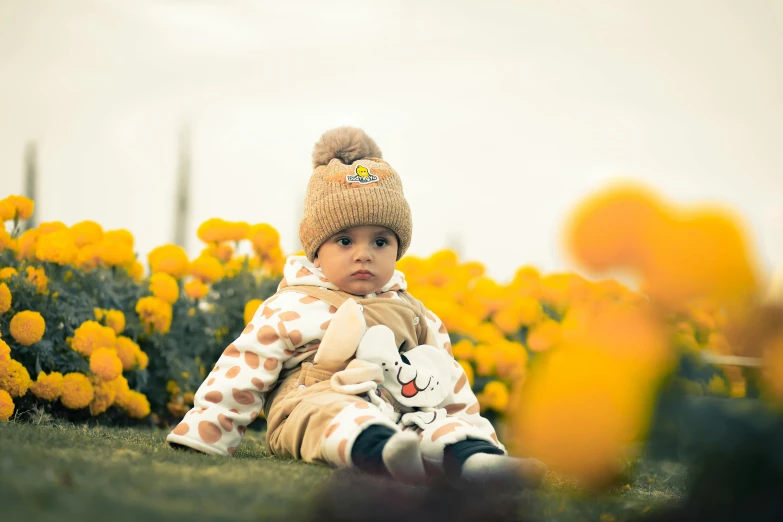 a child sits in a field of flowers with a stuffed animal