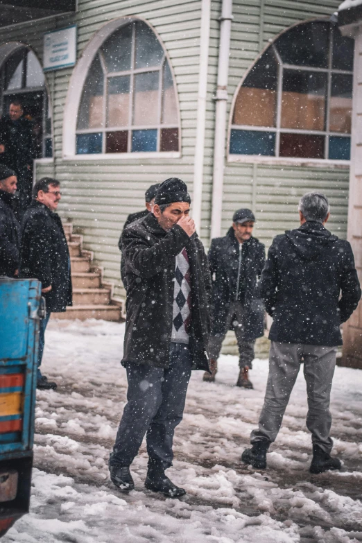 a man talking on a cell phone while standing in the snow