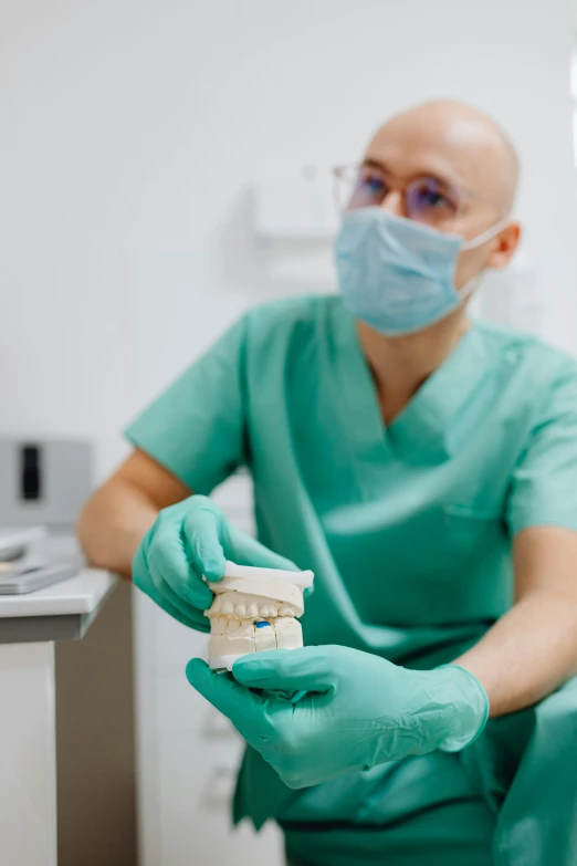 dentist wearing face mask and glove holds out toothbrush