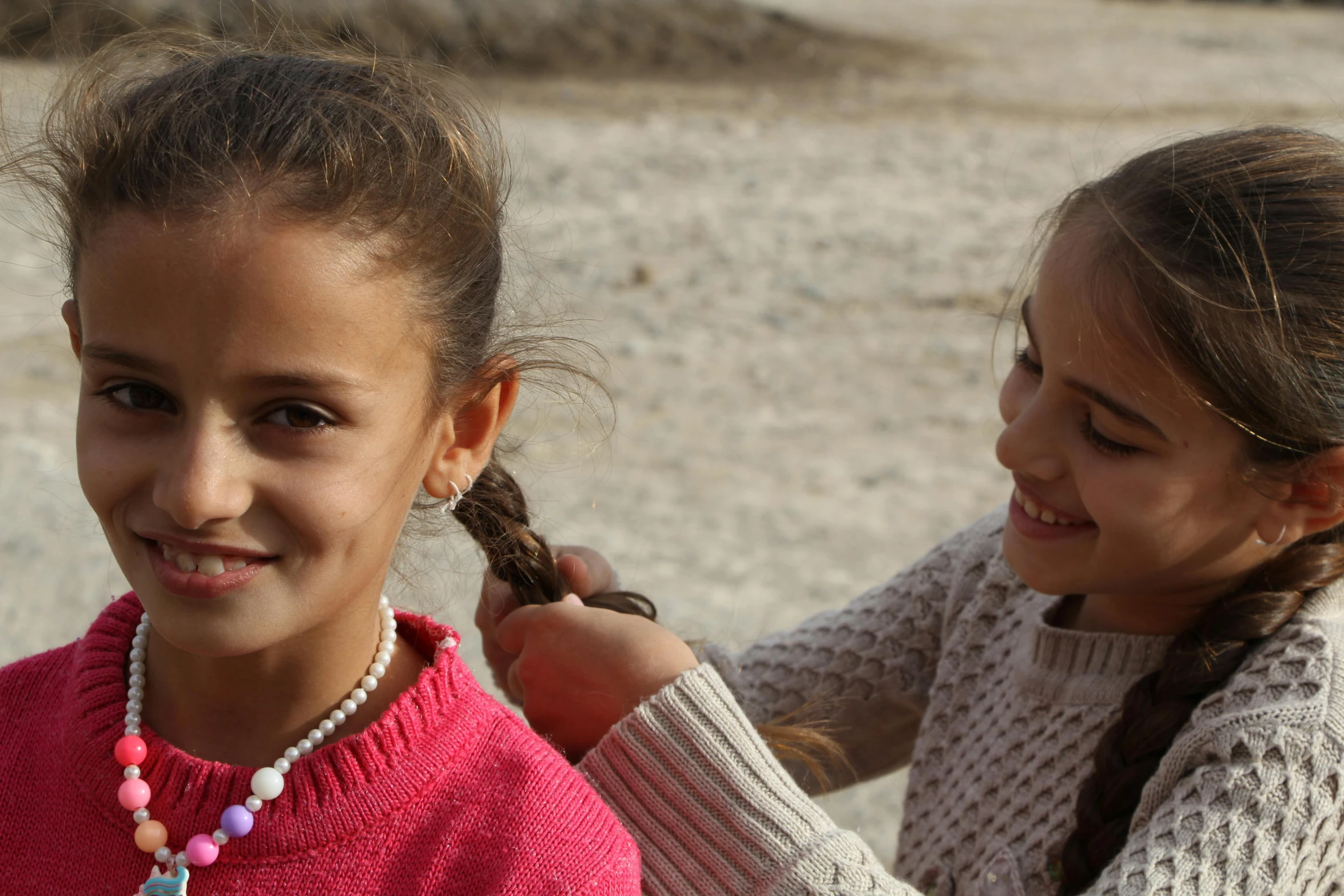 two girls with necklaces on smiling and getting their hair cut