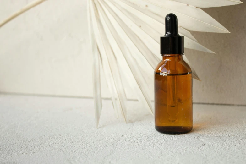 a brown glass bottle with a small white fan sitting next to it