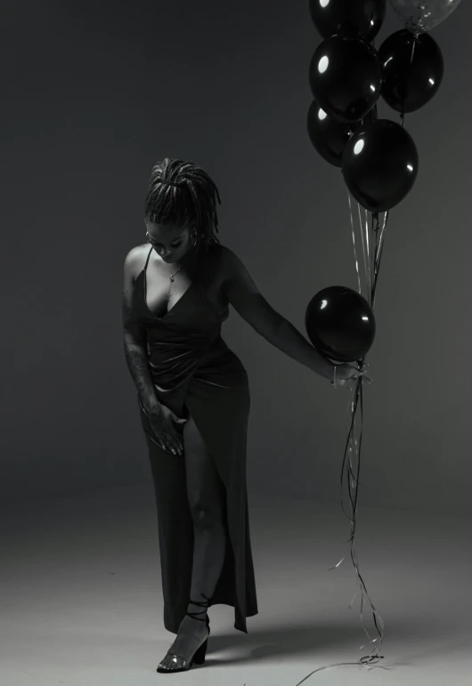 a woman standing on one leg holding a bunch of balloons