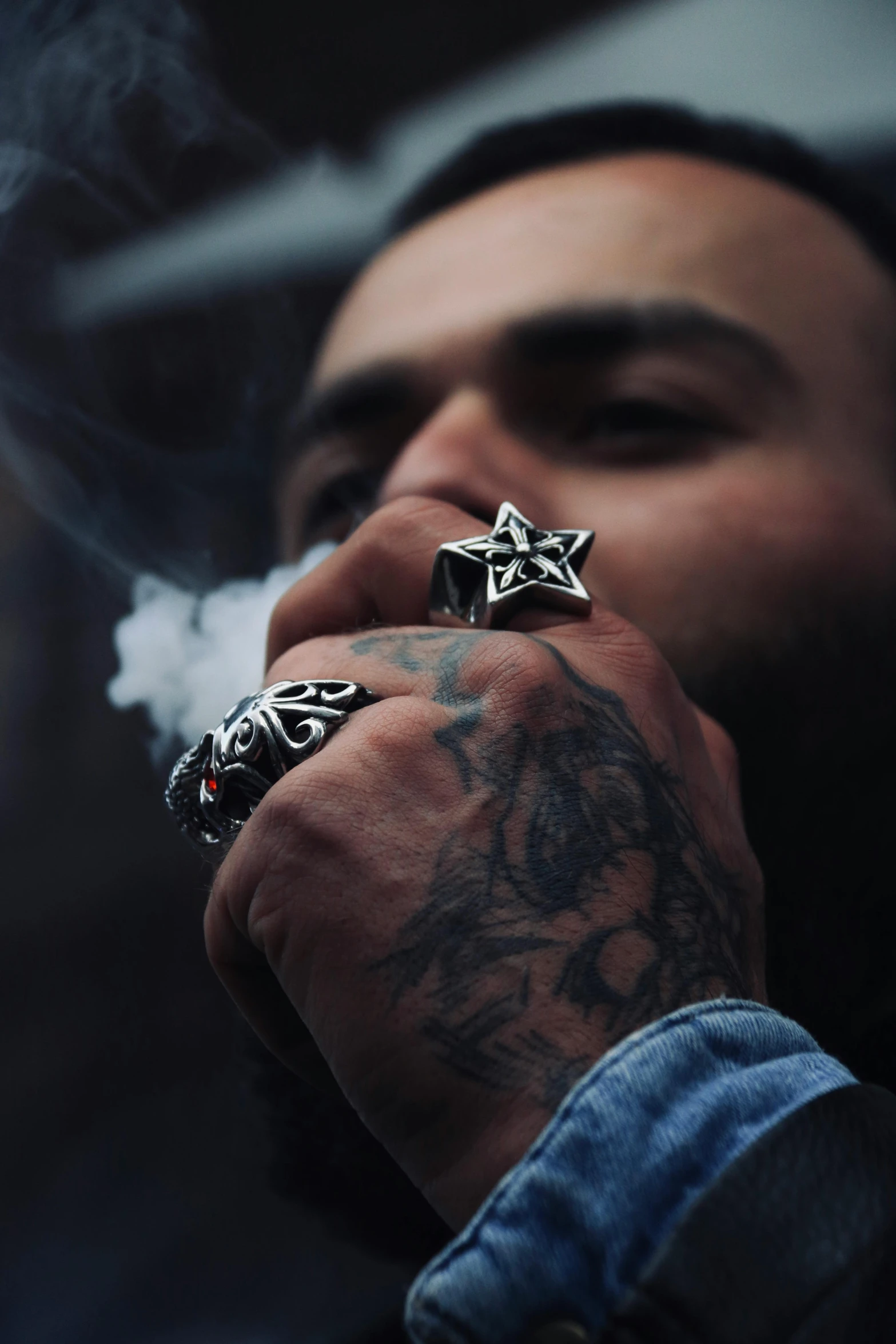 a man smoking an inked cigarette with his hand holding two silver stars