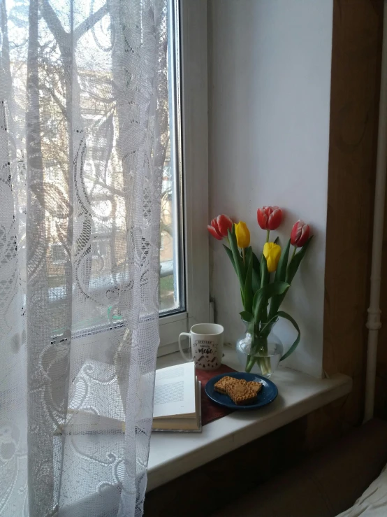 a window sill in a bedroom with flowers and a book