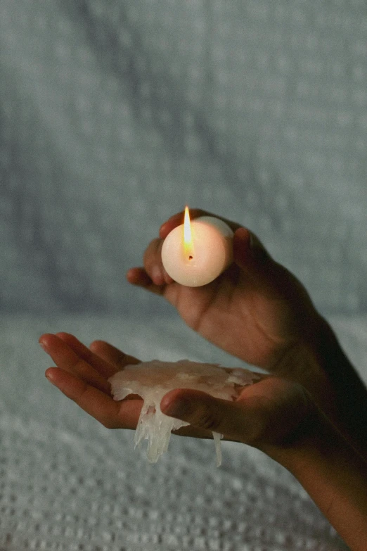 a person holding a lit candle in their hands