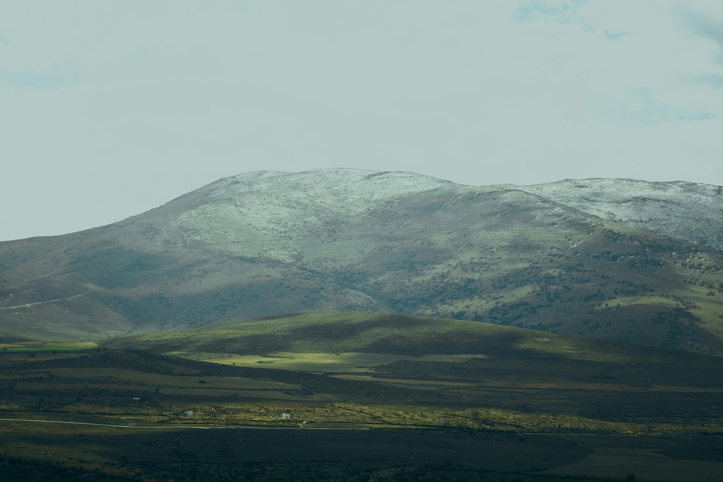 snow covers the mountains and greenery below