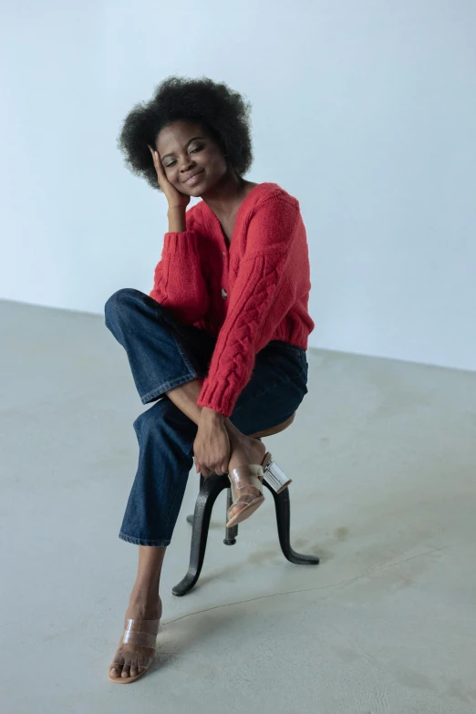 a smiling young african woman is sitting on a chair