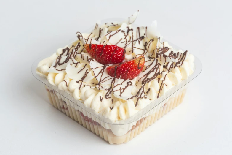 a dessert in a plastic container has cream, strawberries, and whipped cream