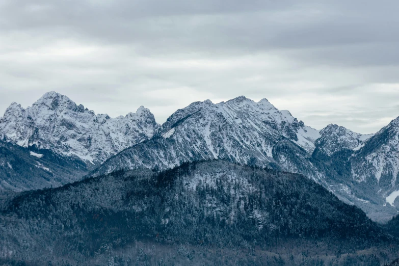 mountains covered with snow and trees on a cloudy day