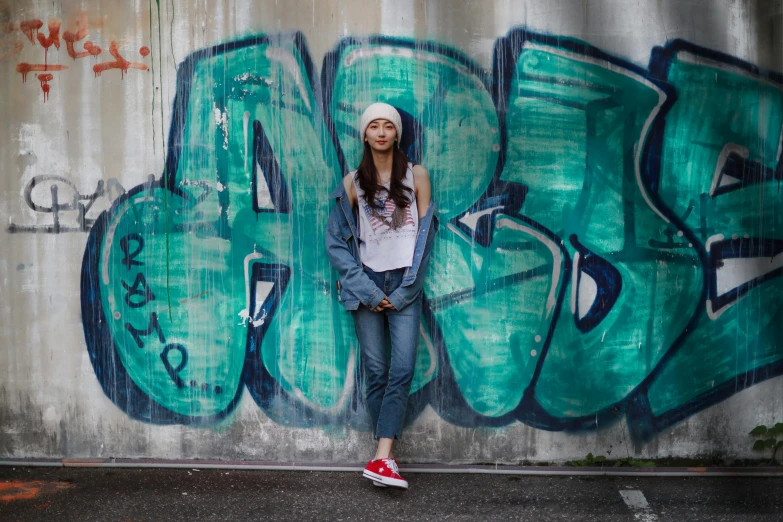 a girl standing in front of graffiti covered wall