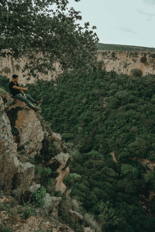 a man sits on top of a hill overlooking a valley