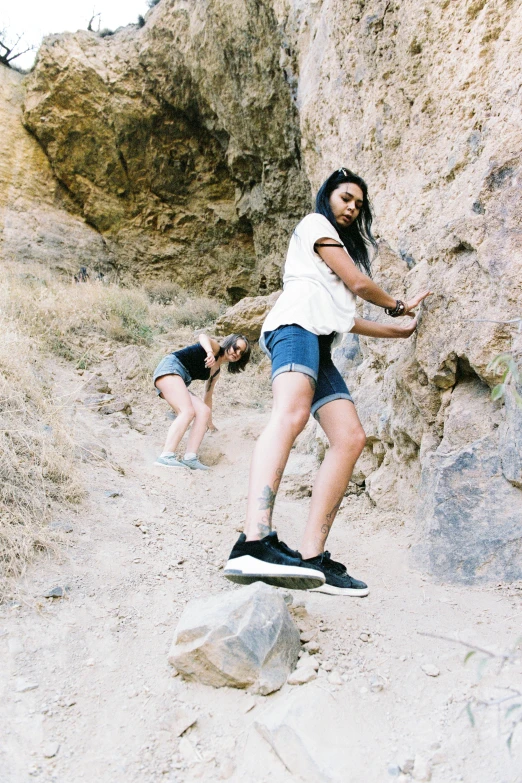 a man in shorts on a skateboard in front of a large rock