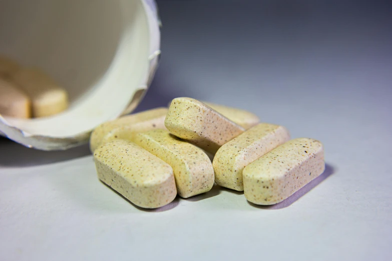 closeup of white pills and an opened medicine container