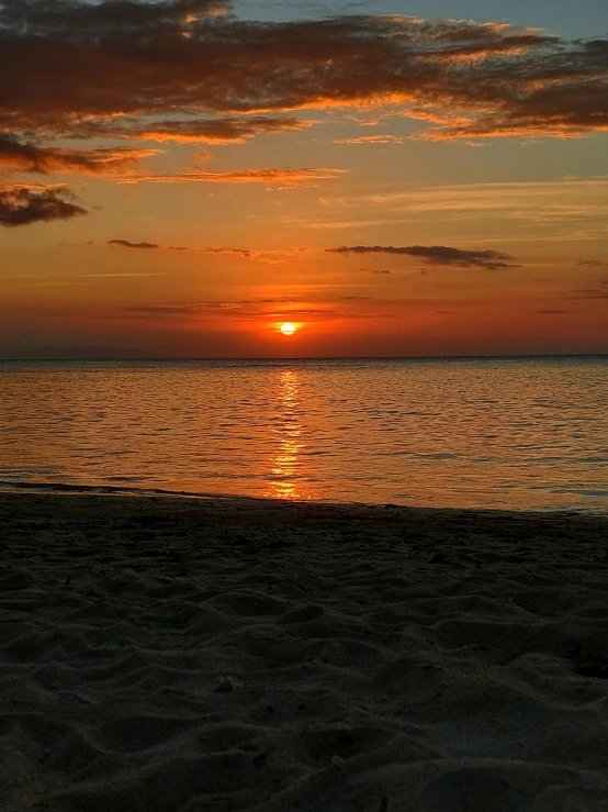 a man on the beach holding his surfboard at sunset