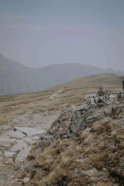 two people are on a mountain top and one person is sitting down looking at soing