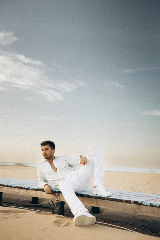 the man is sitting on a rail by the water