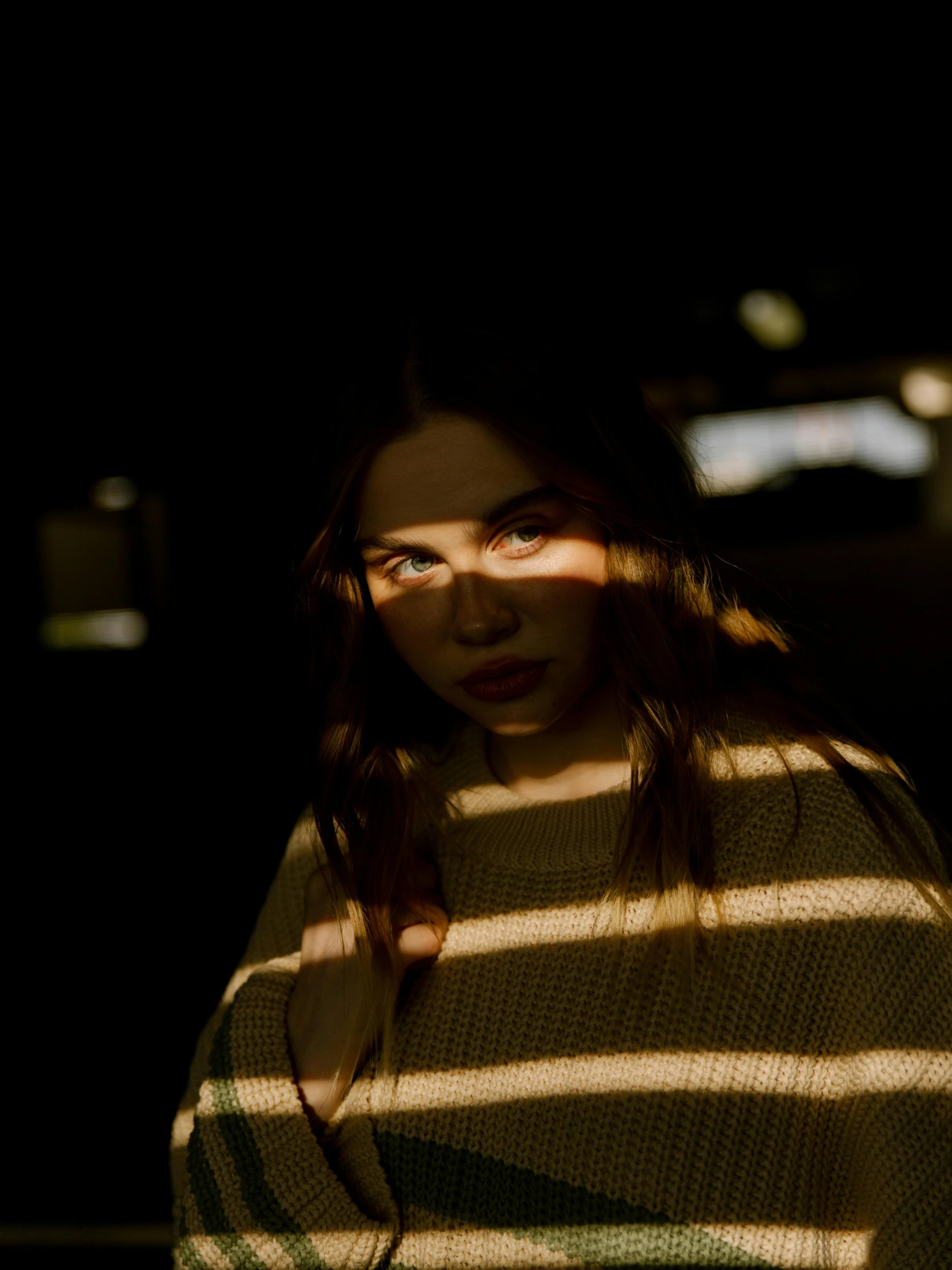 the sunlight shines in on a woman in a green sweater