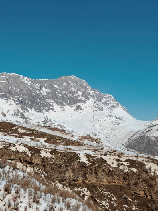 a train on tracks below some snow capped mountains