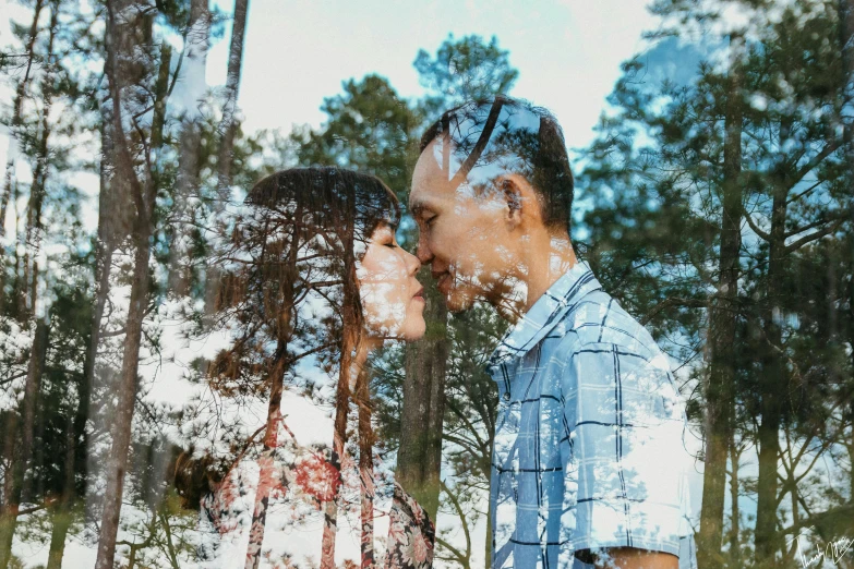 a guy and girl standing by a tree with their faces touching each other