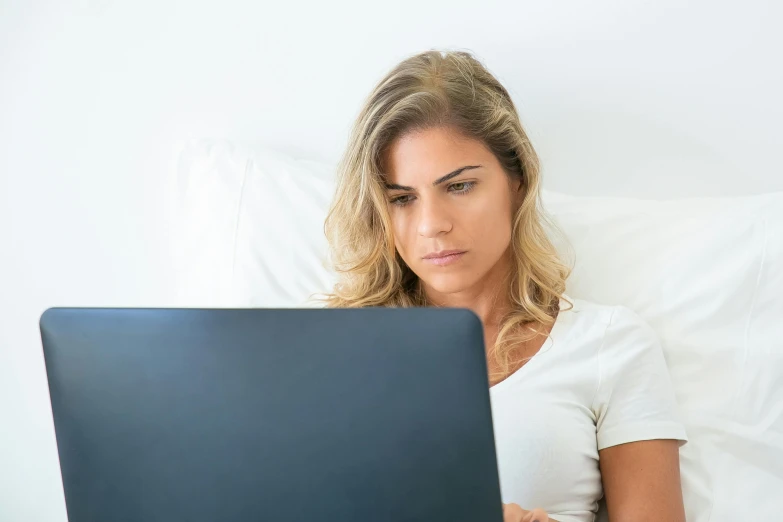 a woman sitting in bed with her lap top and staring at the screen