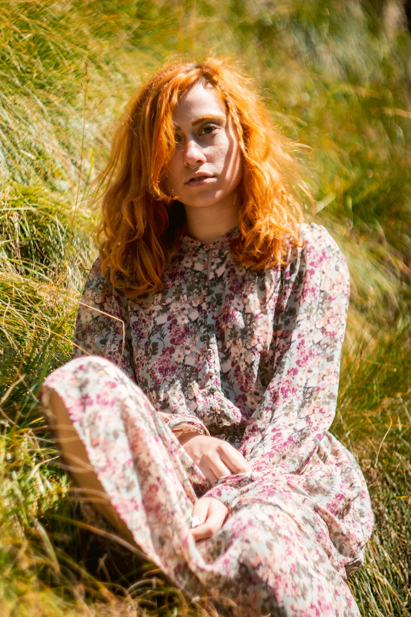a young woman with orange hair sitting in grass