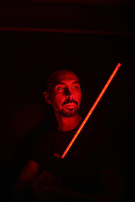 man holding a neon sword in dark room