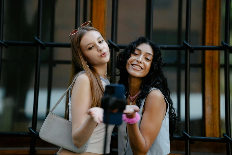 two girls are taking a selfie with a cell phone