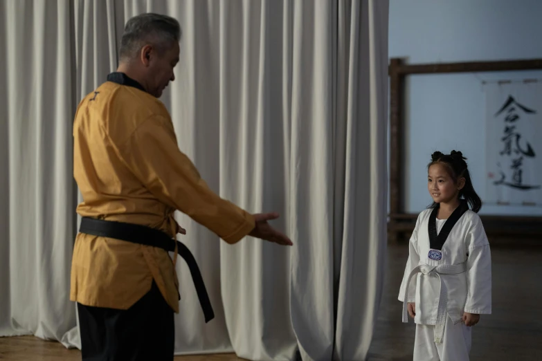 a man standing behind a little girl in a martial stance