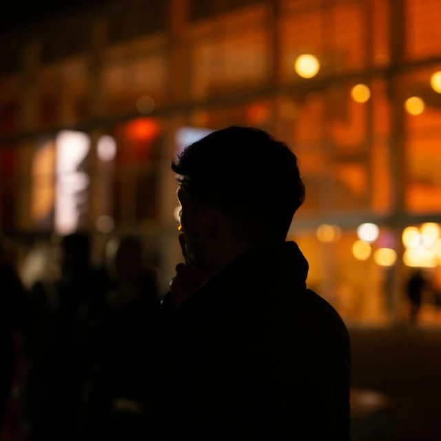 a man standing at the street on a phone at night