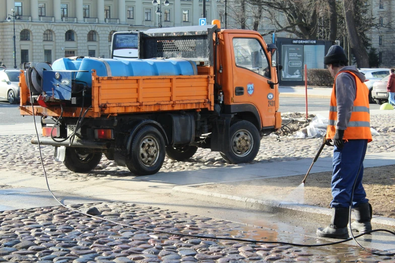 a person in an orange and black vest is cleaning a truck